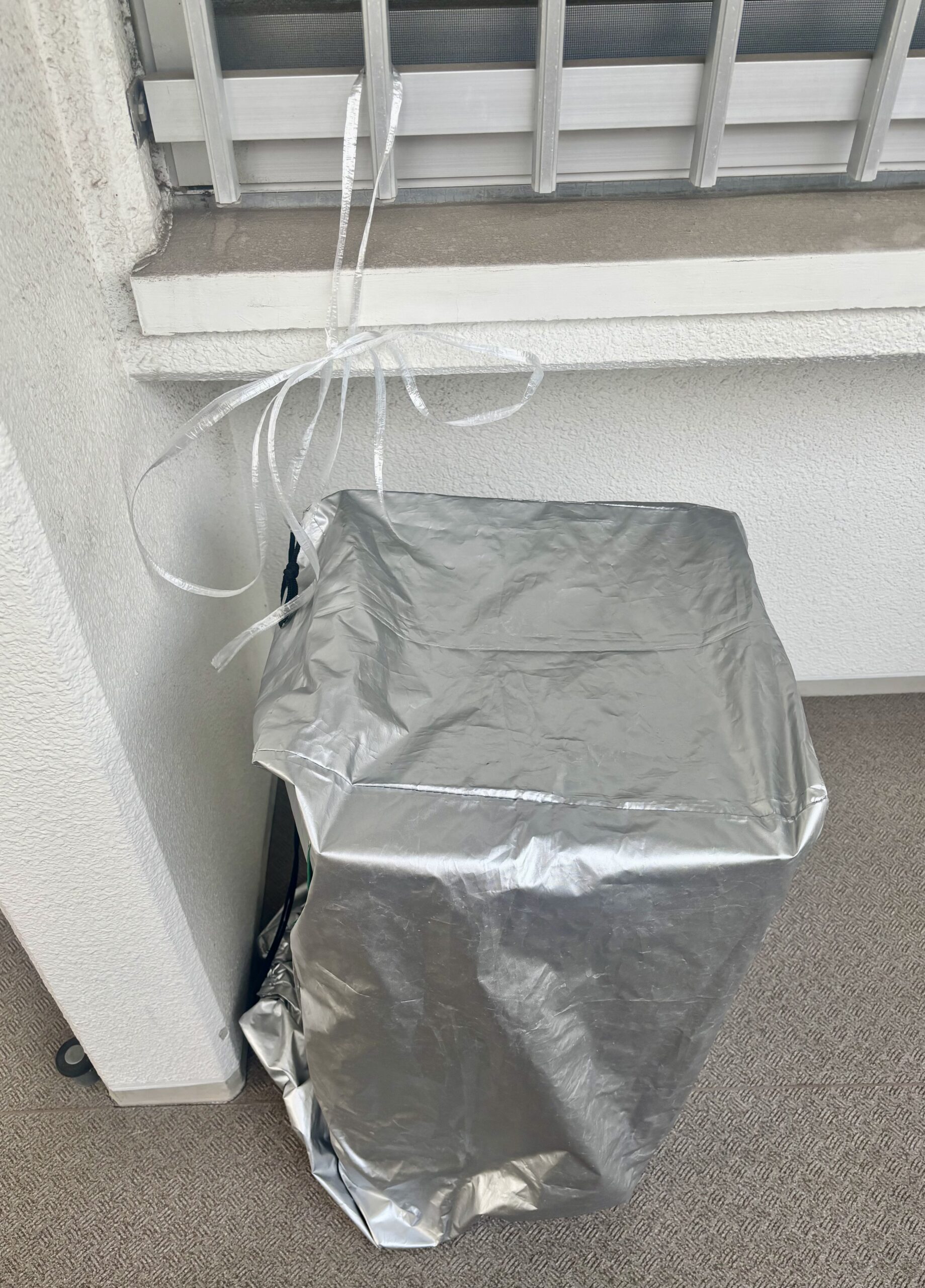 風対策でひもを結んで固定したパルシステムの宅配箱